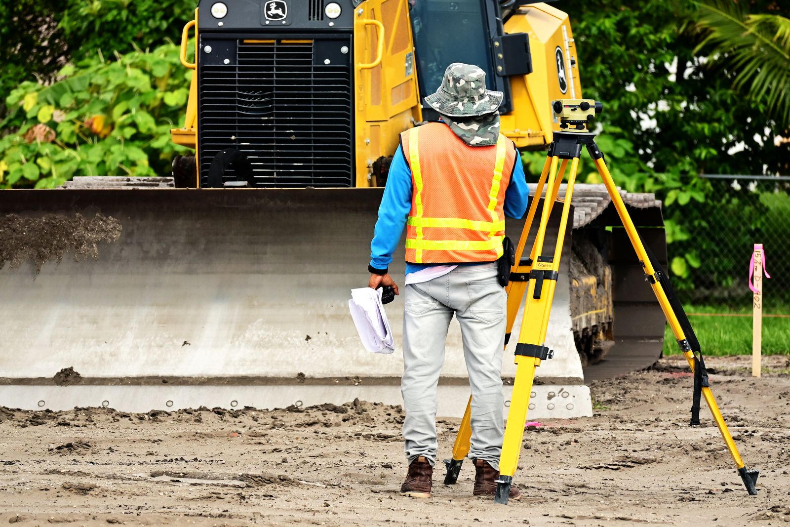 Illustrative surveyor with equipment observing an active construction site, not an actual project