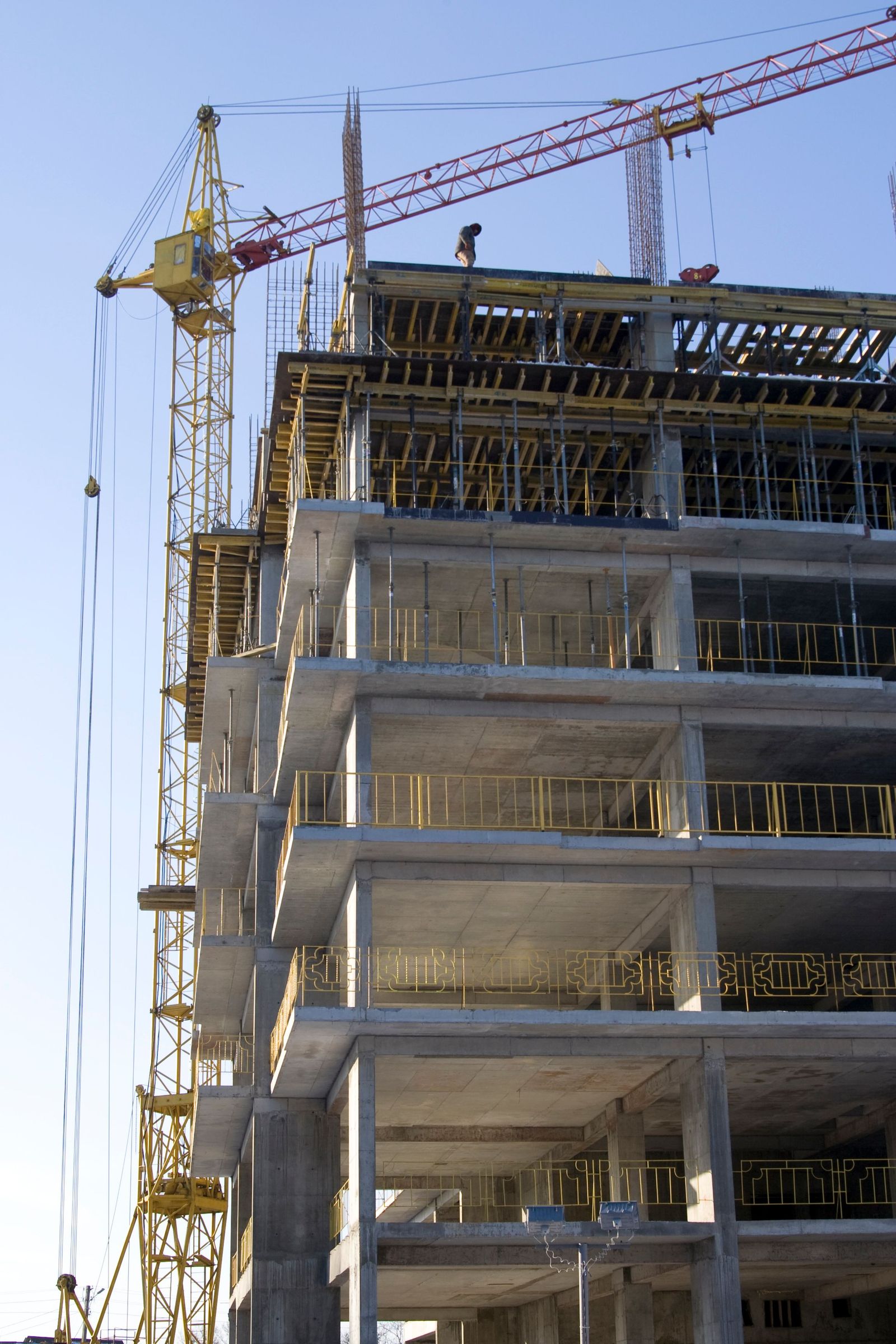 Illustrative concrete-frame office tower under construction with a tower crane, not an actual project